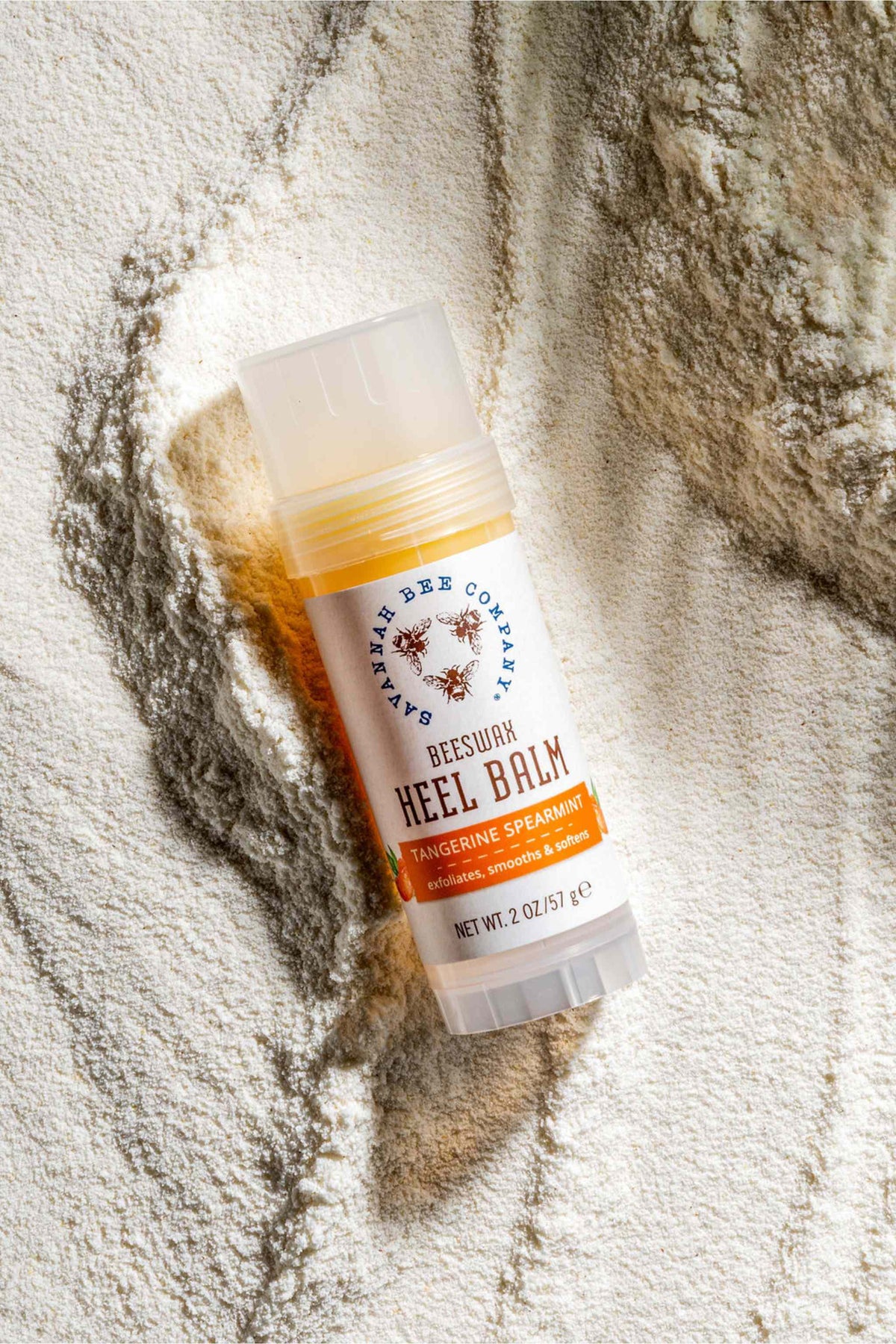 Beeswax Heel Balm Tangerine Spearmint 2 oz. on top of sand.