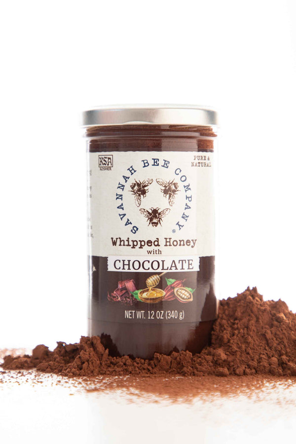 Whipped Honey With Chocolate 12 ounce jar next to chocolate powder on white background.